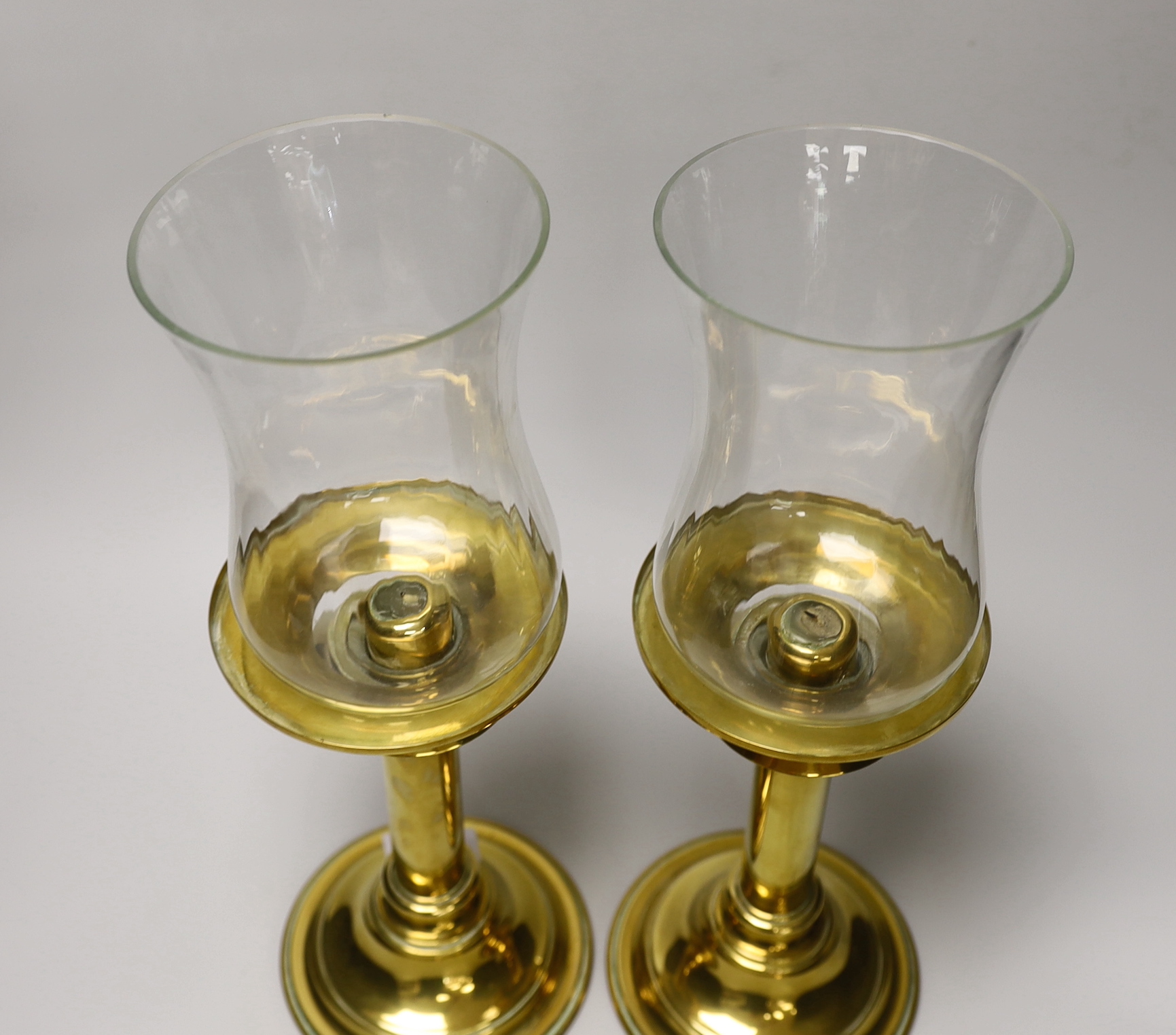 A pair of brass candlesticks with spring loading actions and storm shades and a Victorian cast brass adjustable reading stand with pierced and embossed decoration, the largest each 37cm high